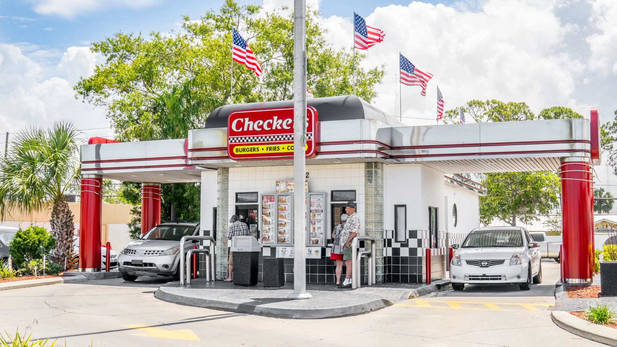 Ground-level photograph of a single-tenant Checkers double drive-through restaurant with retro diner architecture and customer service windows
