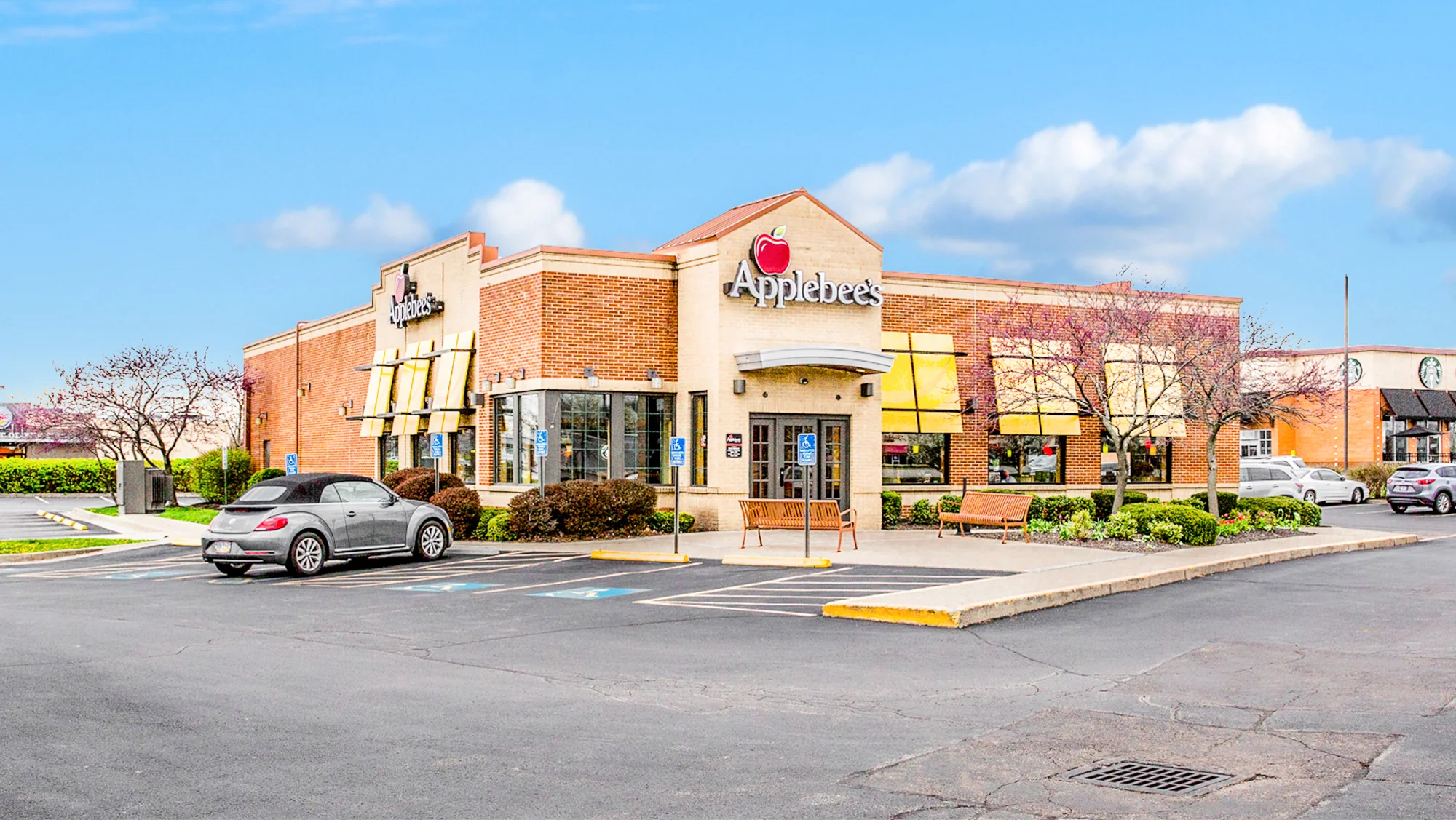 Ground-level photograph of a single-tenant Applebee's restaurant with brick exterior, pitched-roof entrance tower, branded signage, and customer parking