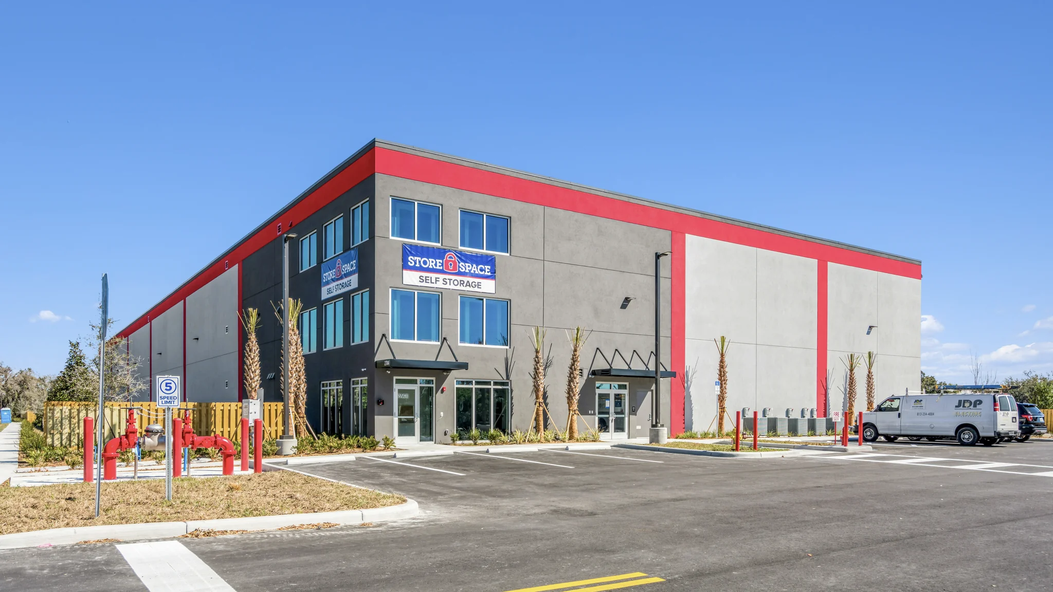 Ground-level photograph of a single-tenant Store Space Self Storage facility with multi-story climate-controlled building, branded signage, and customer parking