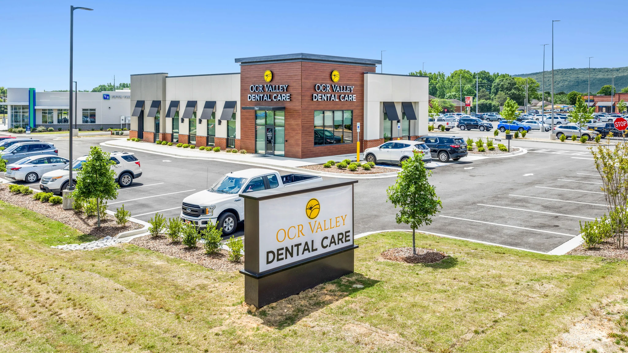 Ground-level photograph of a single-tenant Fastpace Health urgent care building with corner entrance, urgent care signage, and patient parking