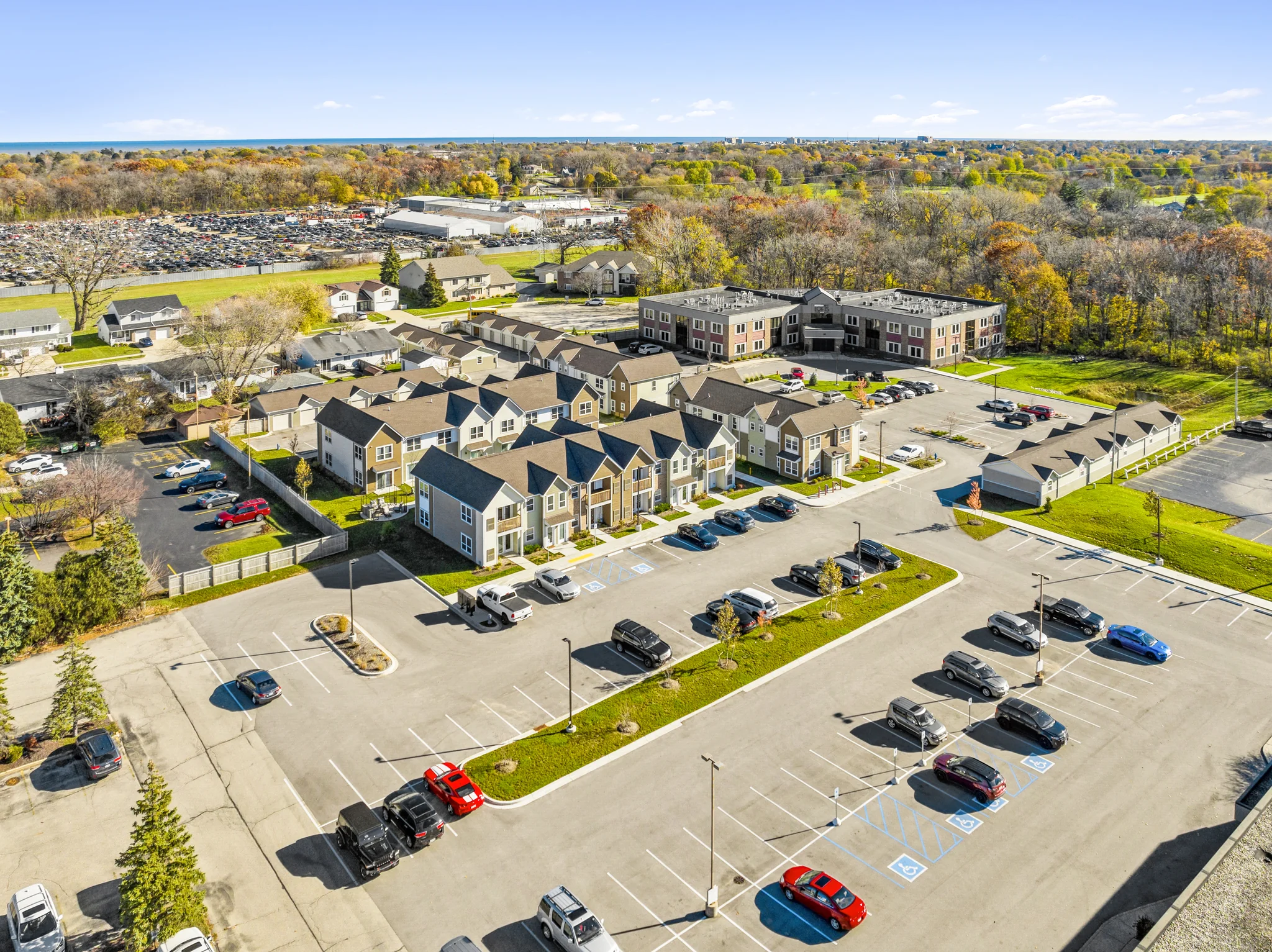 Aerial view of build-to-rent townhouse community with shared parking and adjacent senior living