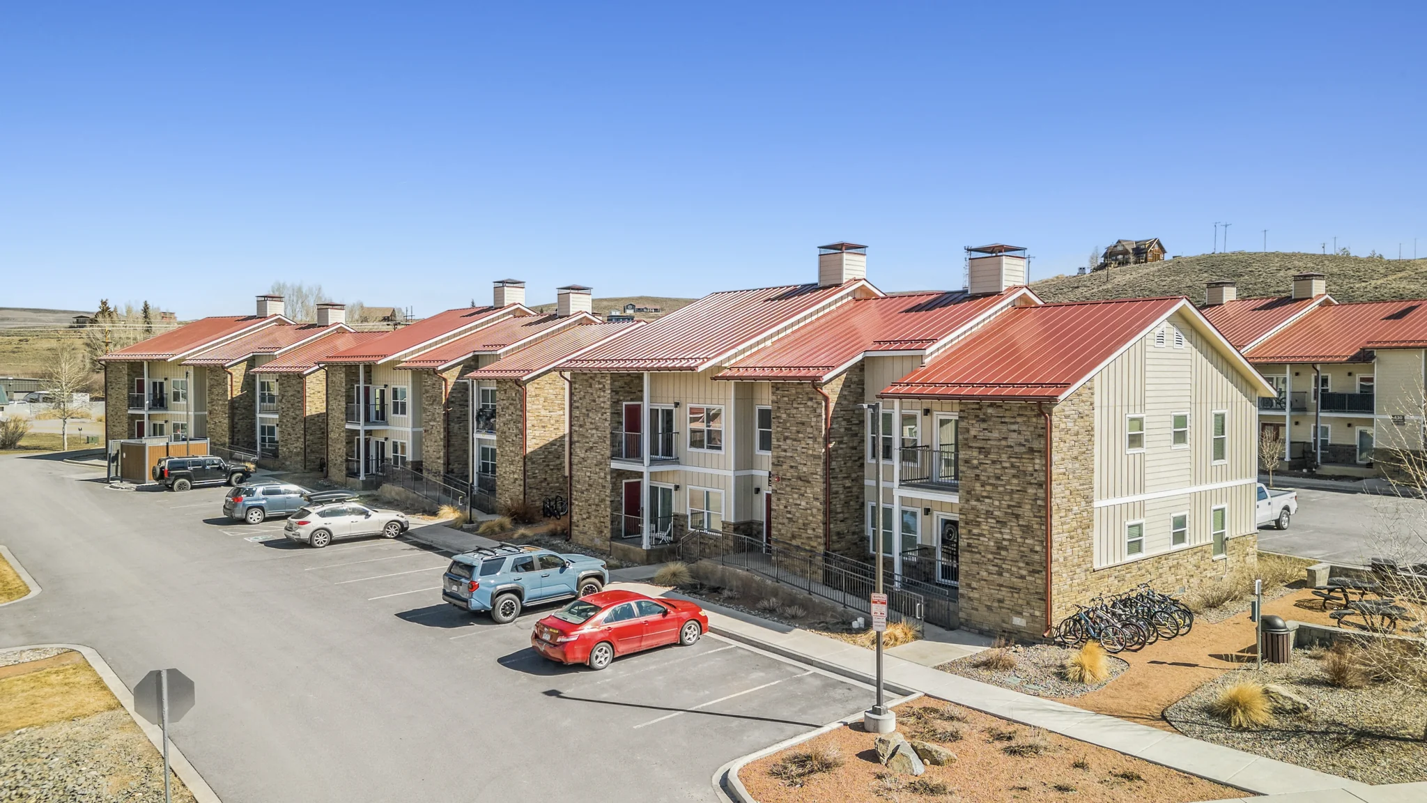 Modern two-story townhouse-style rental community with red metal roofs in Rocky Mountain setting