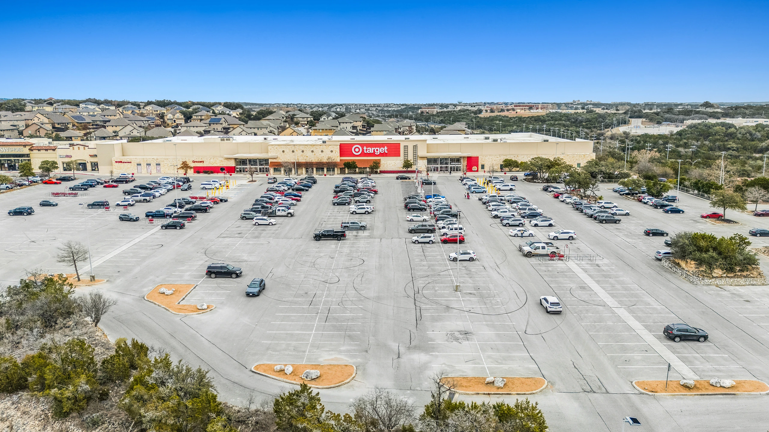 Aerial photograph of a big-box anchored multi-tenant shopping center with expansive customer parking field
