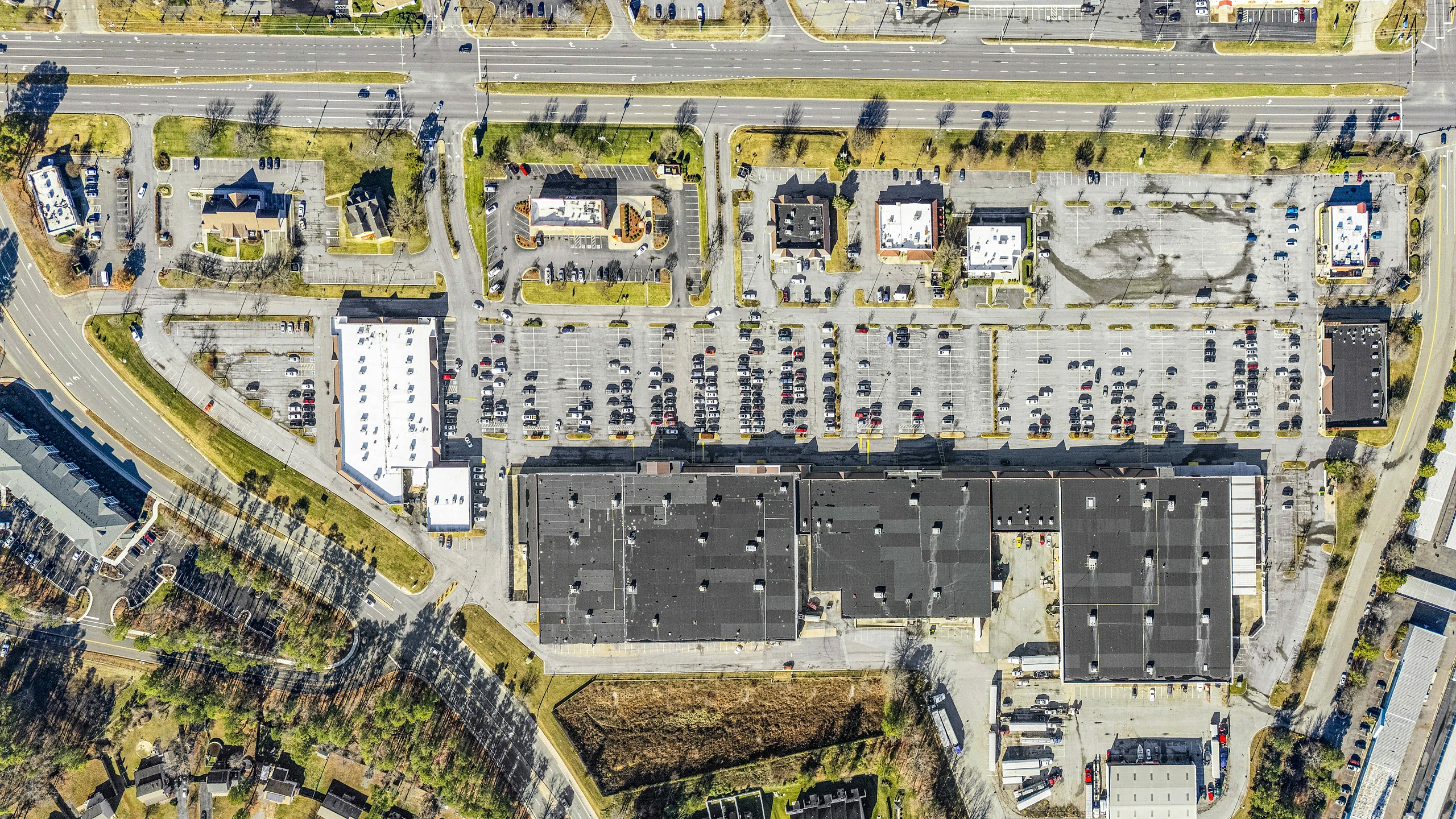 Overhead eagle-eye aerial of a big-box anchored retail center showing full building footprint and parking layout