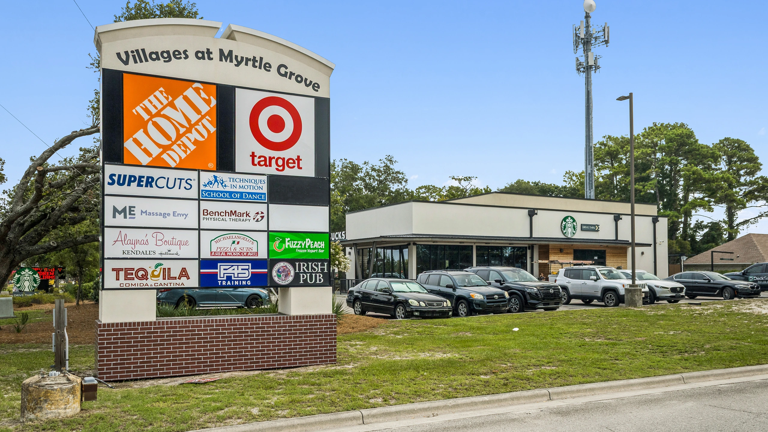 Ground-level photograph of a multi-tenant center monument sign displaying big-box anchor and inline tenant branding