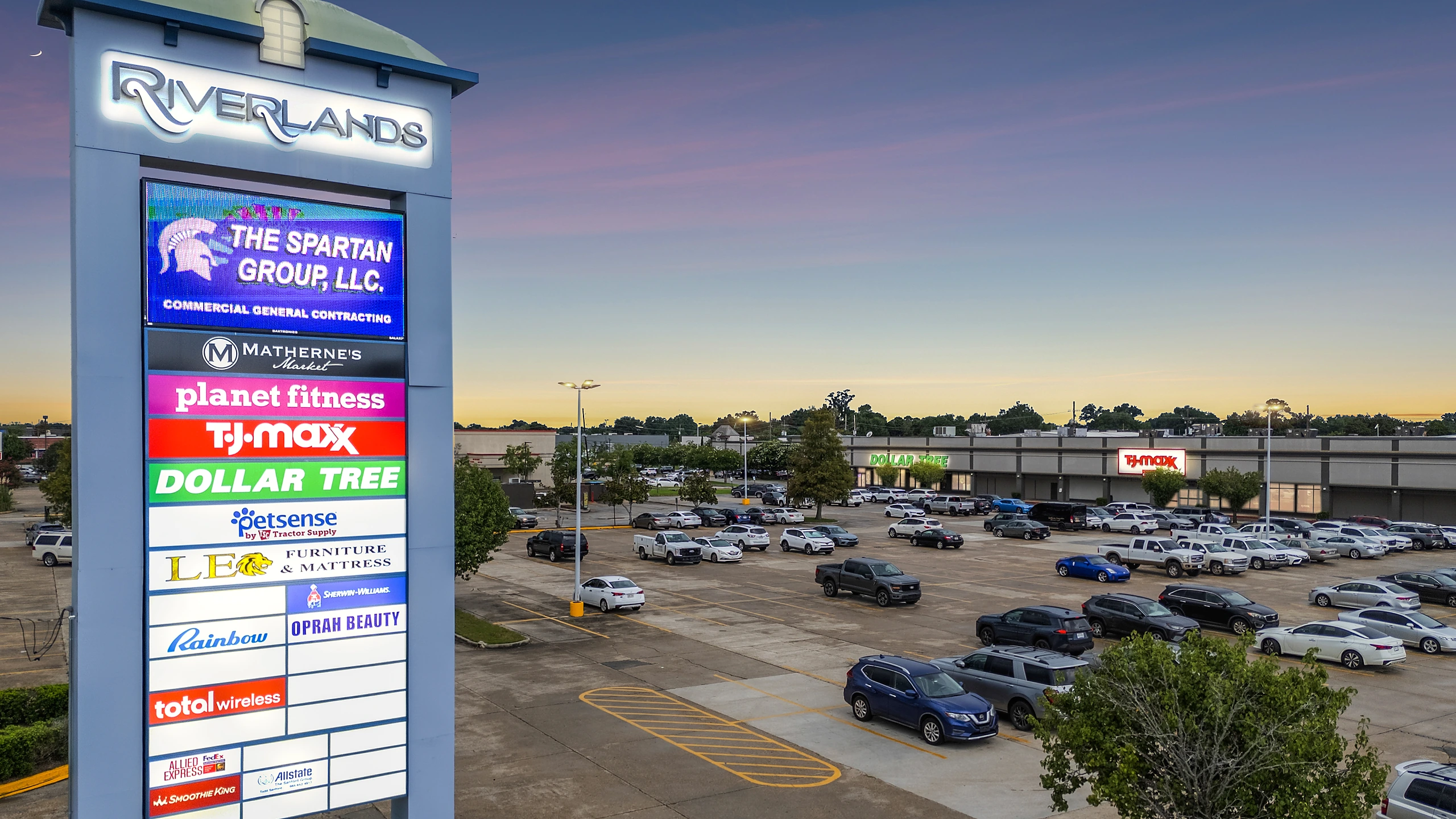 Twilight photograph of a multi-tenant shopping center pylon sign listing national and local tenants