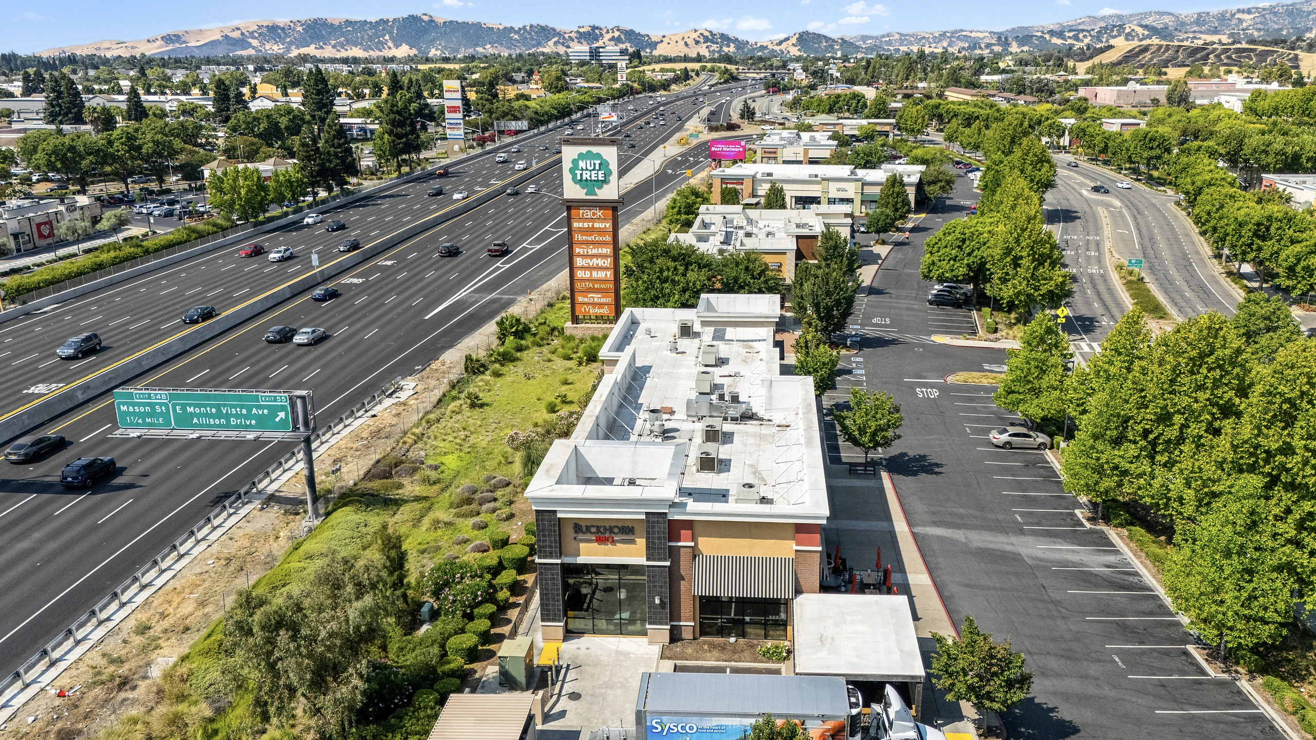 Aerial photograph of a multi-tenant retail center with direct freeway frontage and highway pylon signage