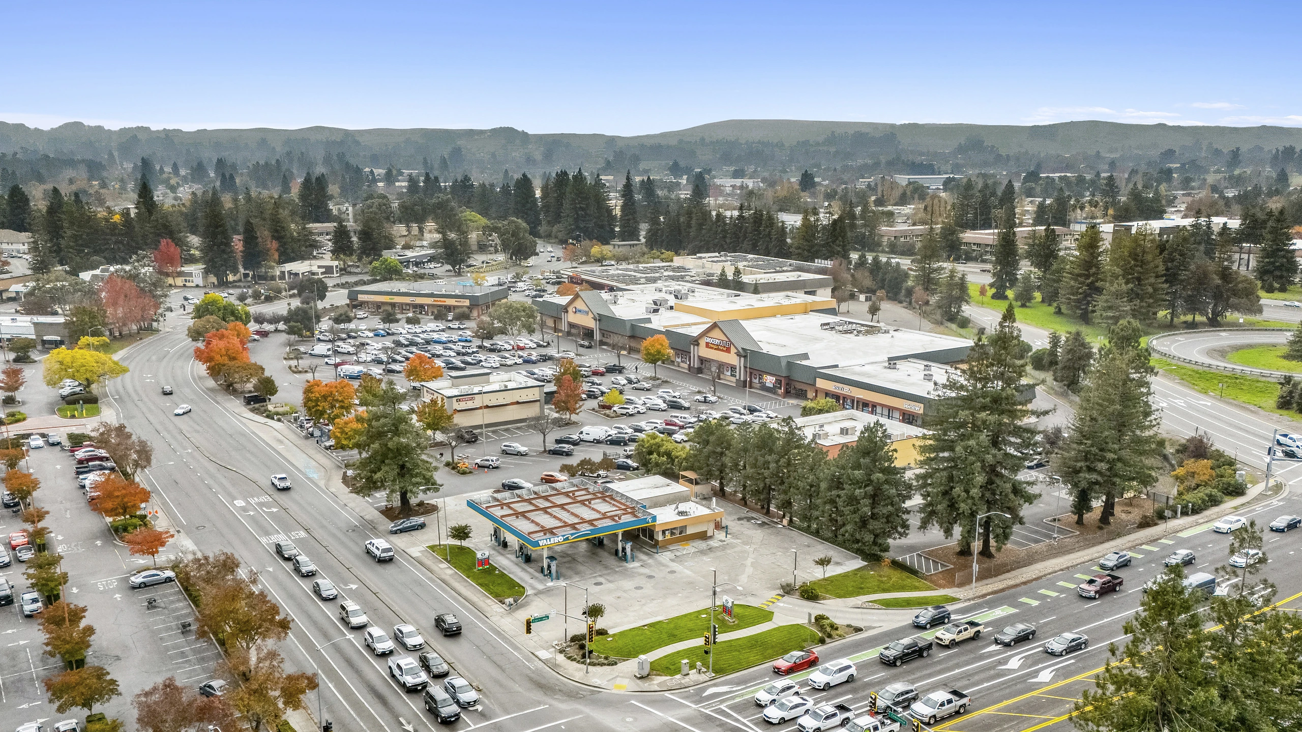 Aerial photograph of a power center at a signalized corner intersection with fuel station outparcel and category-dominant retail tenants