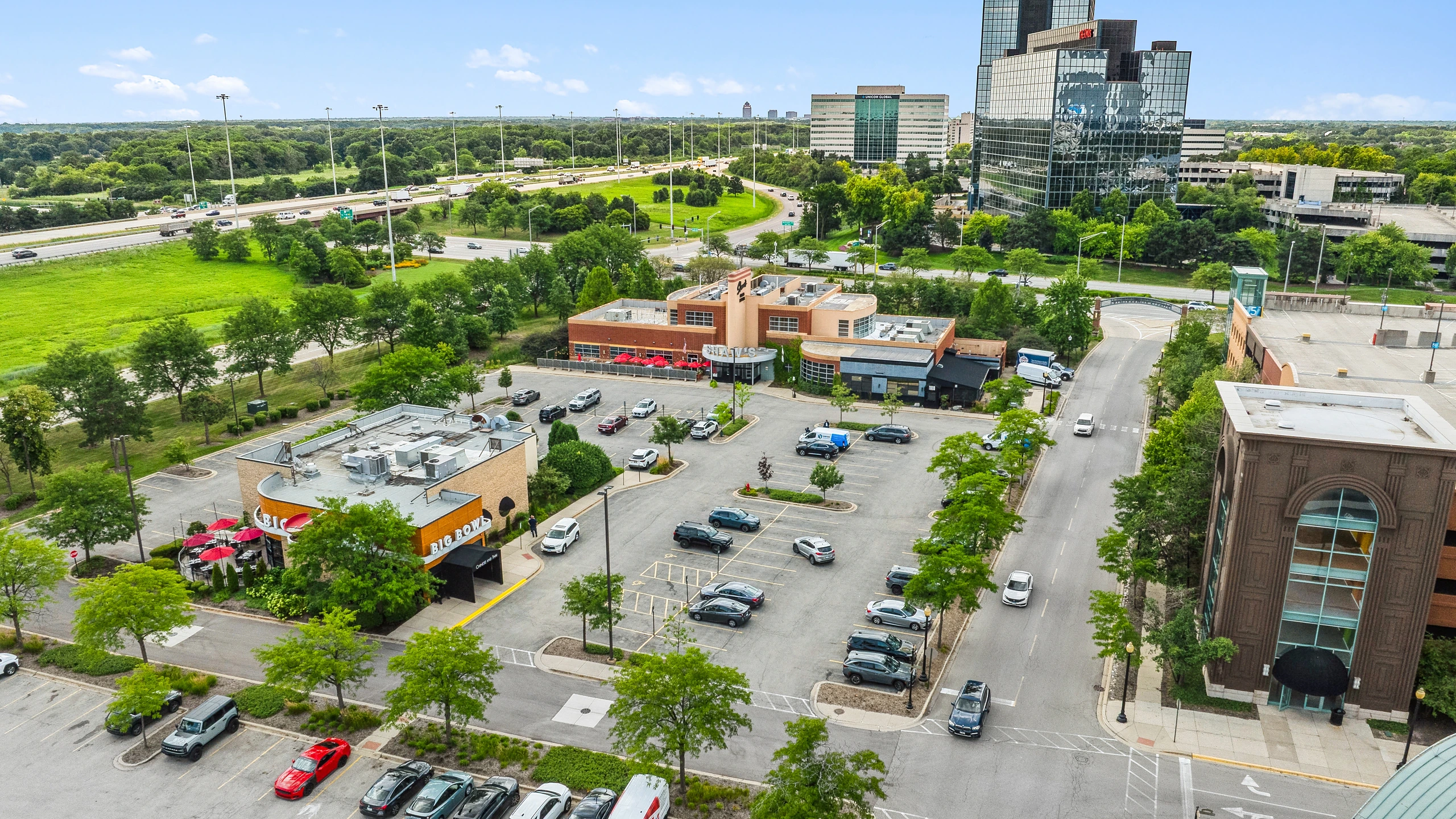 Aerial photograph of a mixed-use retail district with structured parking and city skyline in the background
