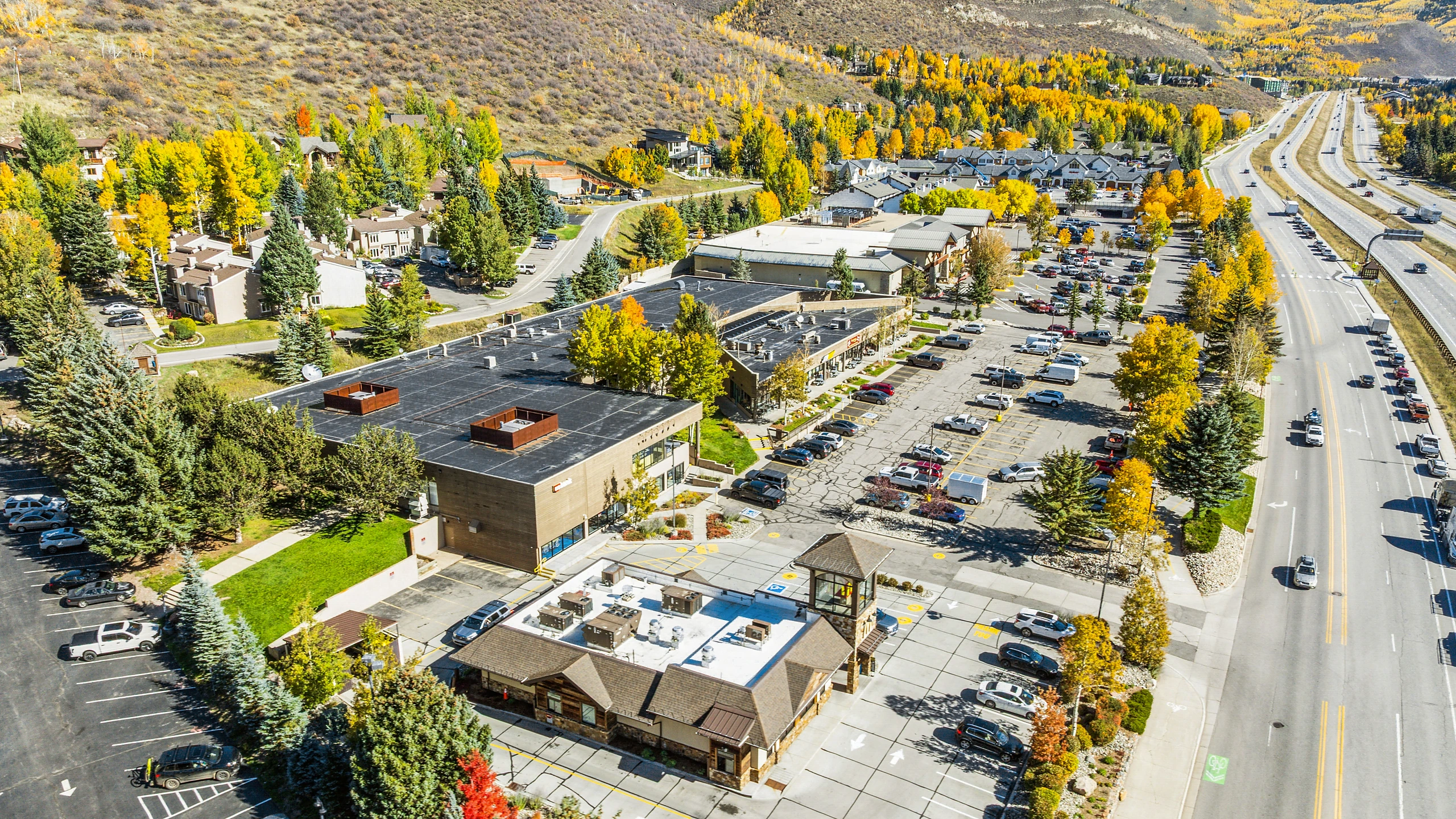 Aerial photograph of a large-format retail center with dining and lodging tenants and highway access
