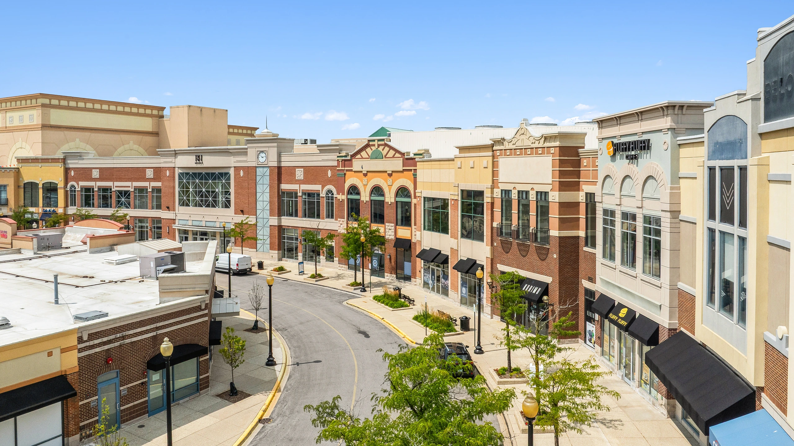 Ground-level photograph of an open-air retail streetscape with pedestrian walkways and multi-story storefronts