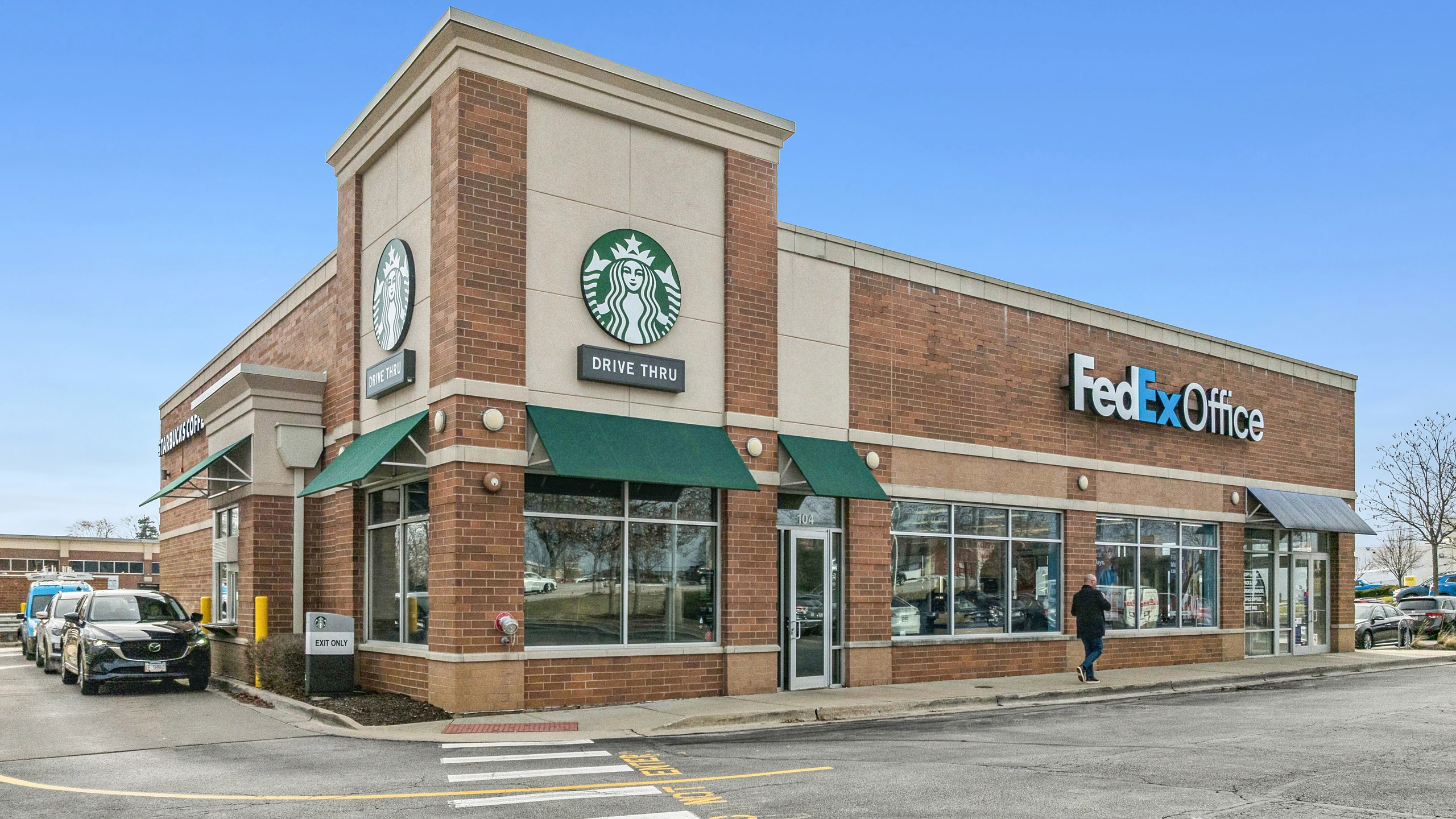 Ground-level photograph of a multi-tenant outparcel building with coffee and shipping service tenants