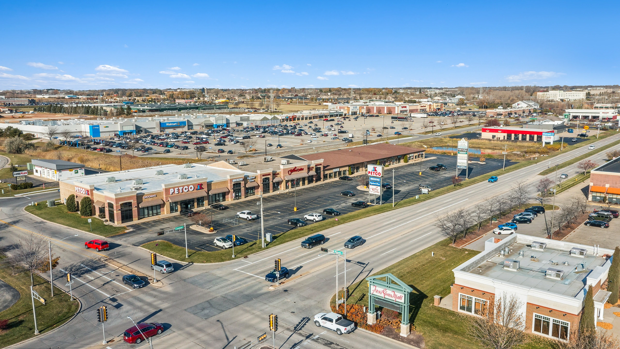 Aerial photograph of a big-box anchored retail corridor with multiple anchor buildings, pad sites, and arterial road frontage