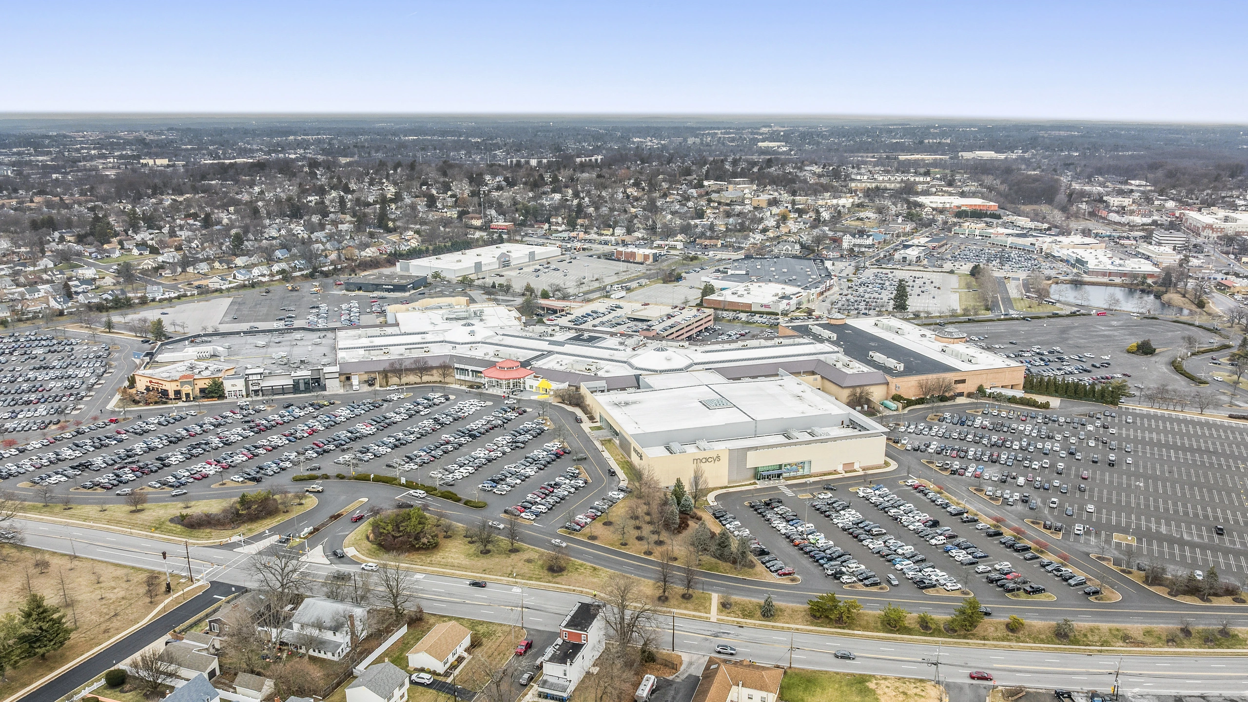 High-altitude aerial of a regional mall showing department store anchors, enclosed inline wings, and surrounding parking