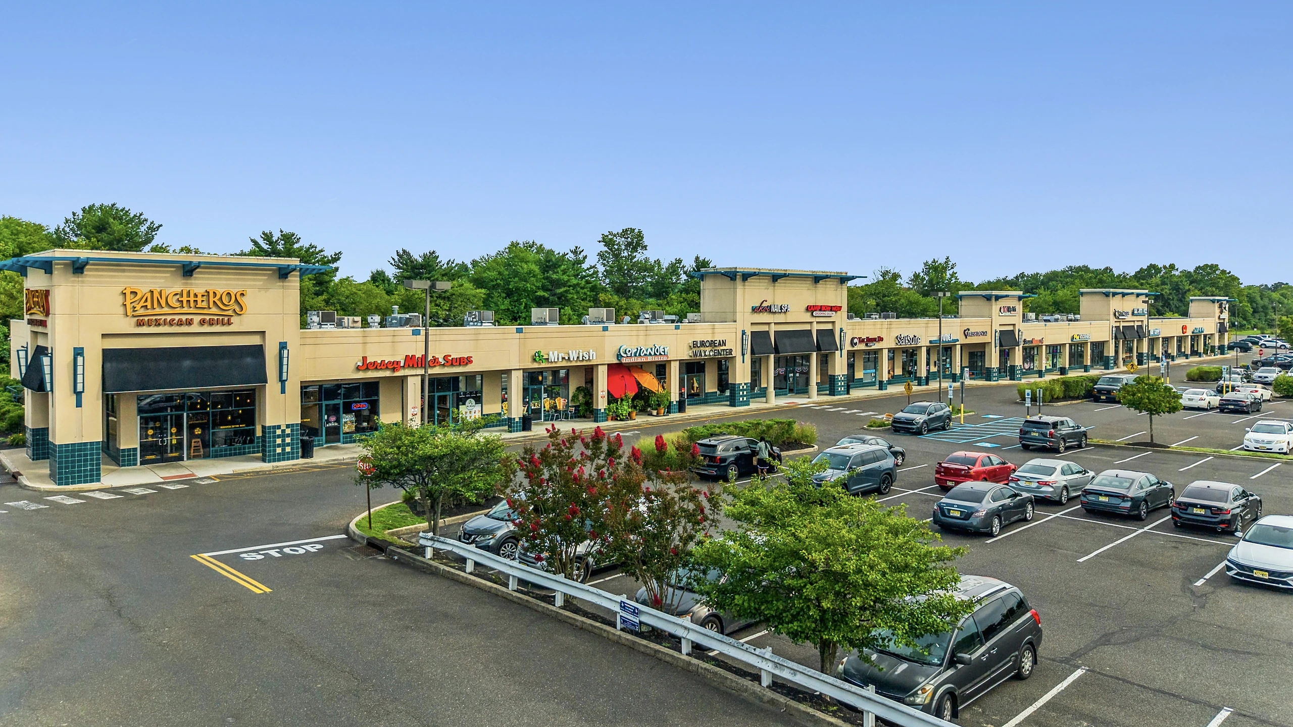 Low aerial photograph of an inline retail center with restaurant and service tenants and customer parking