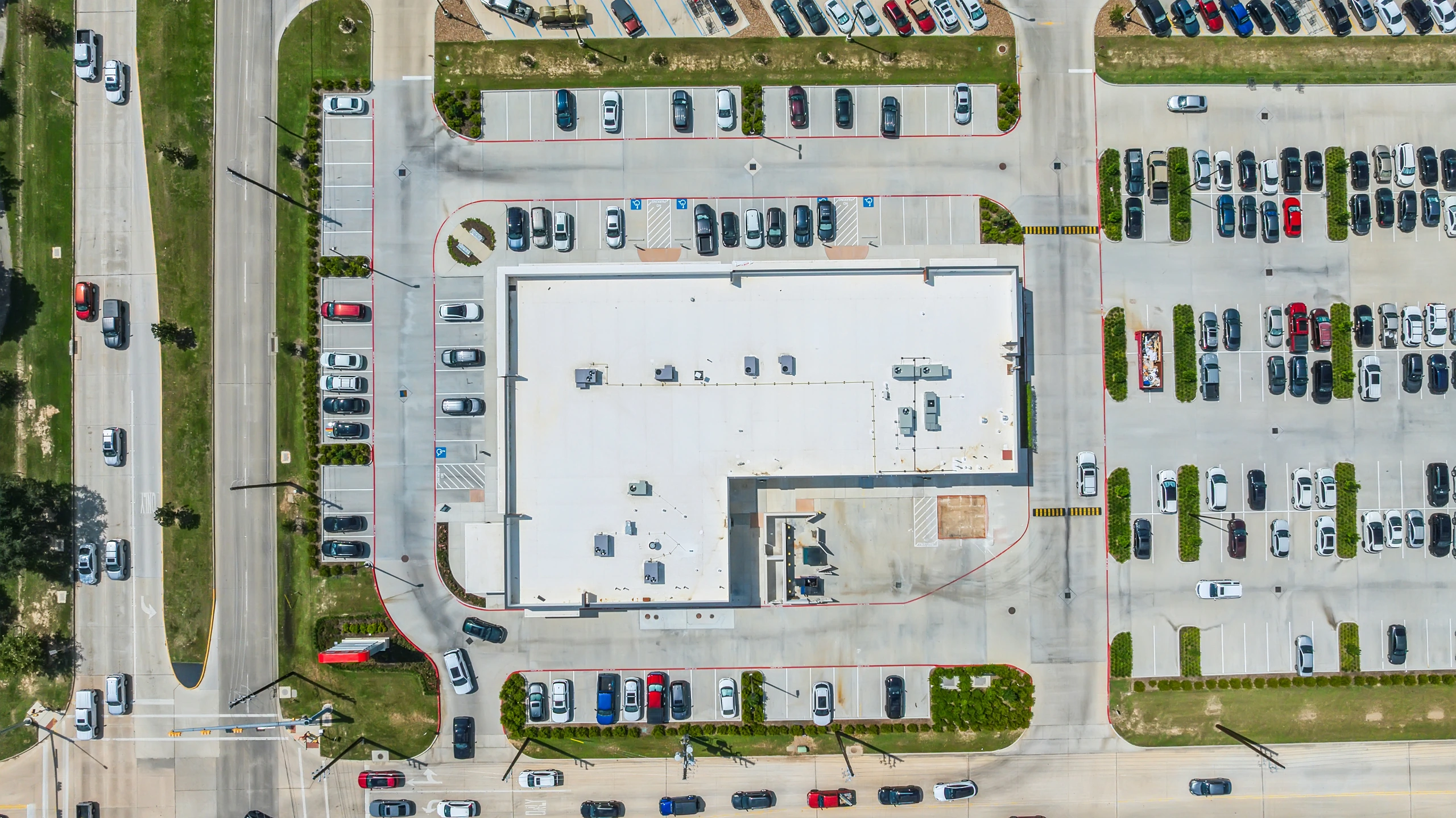 Overhead eagle-eye aerial of a multi-tenant retail building showing roof footprint, drive aisles, and parking count