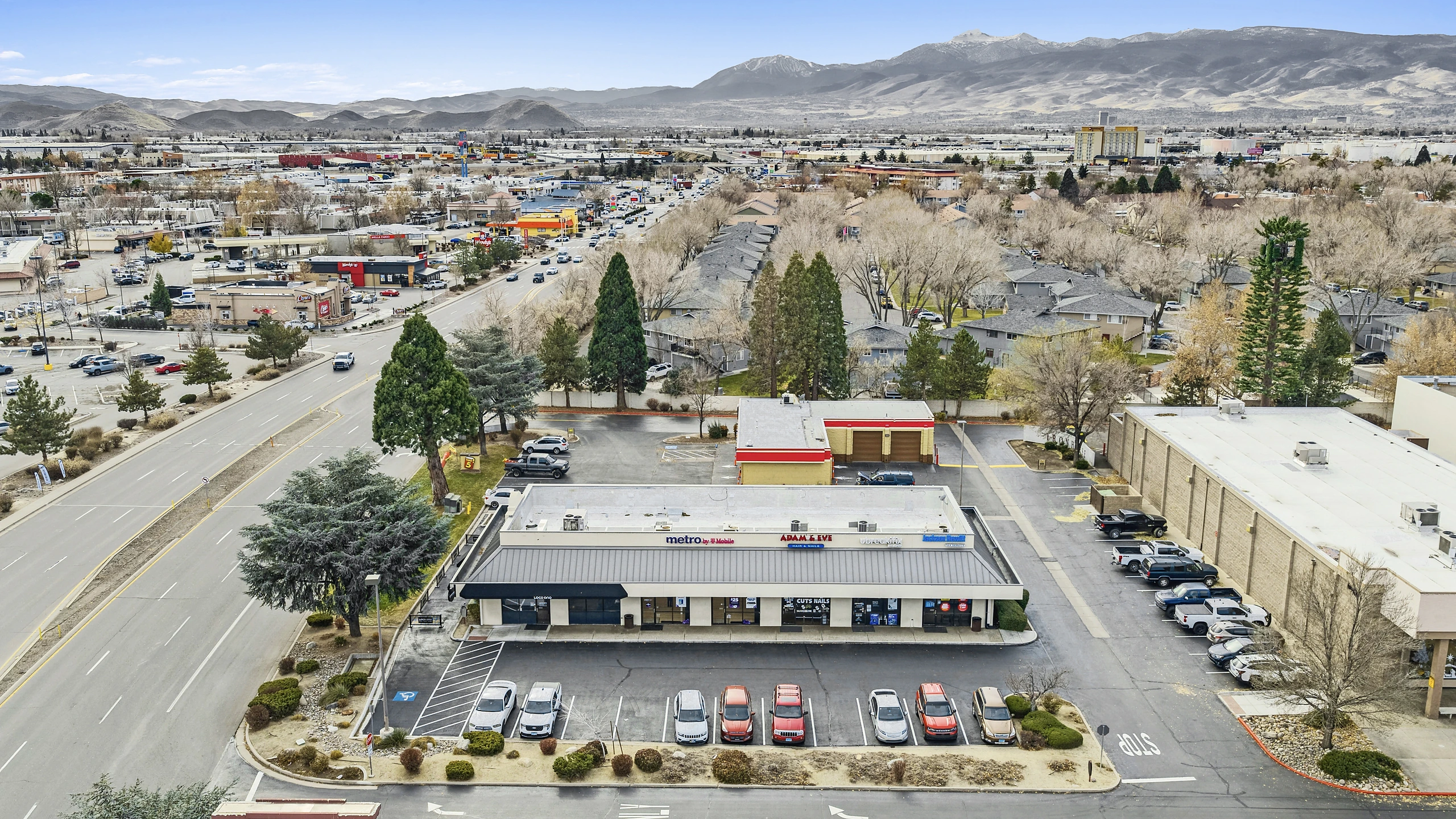 Aerial photograph of a small unanchored strip center with service tenants and mountain backdrop