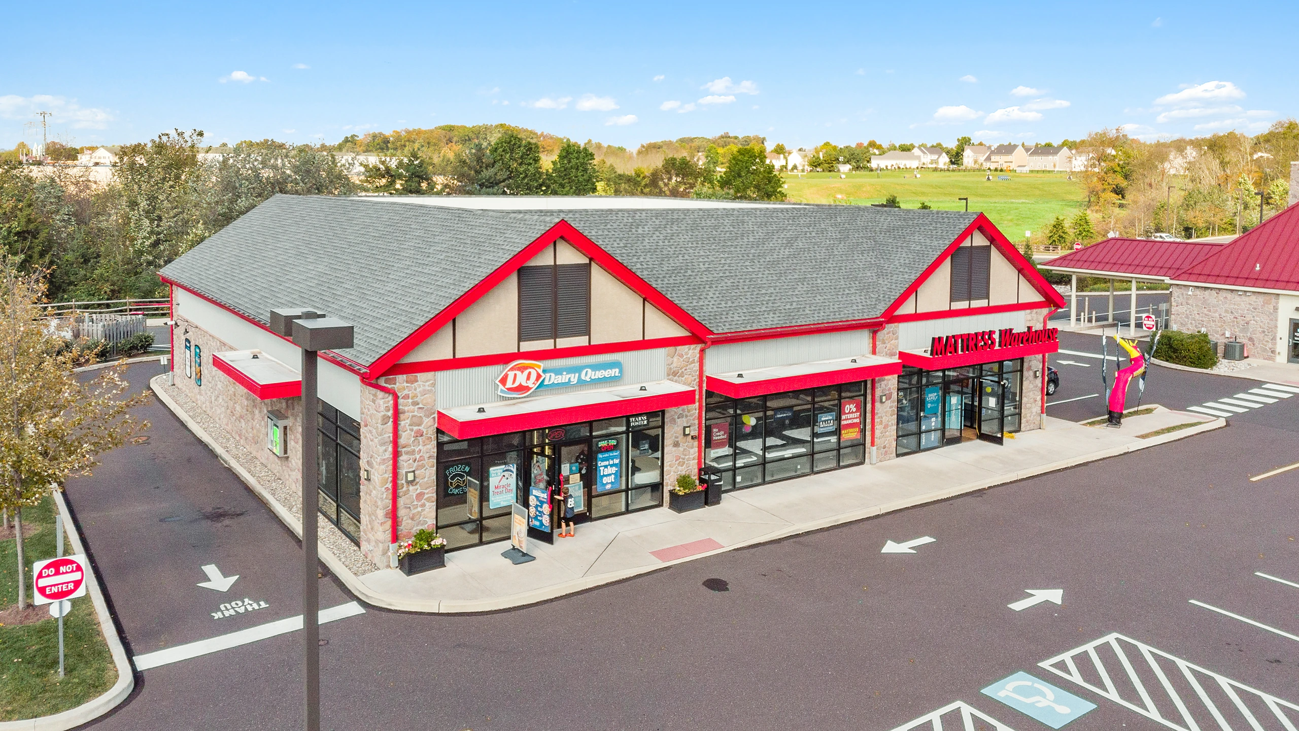 Low aerial photograph of a strip center with red awning storefronts and customer parking