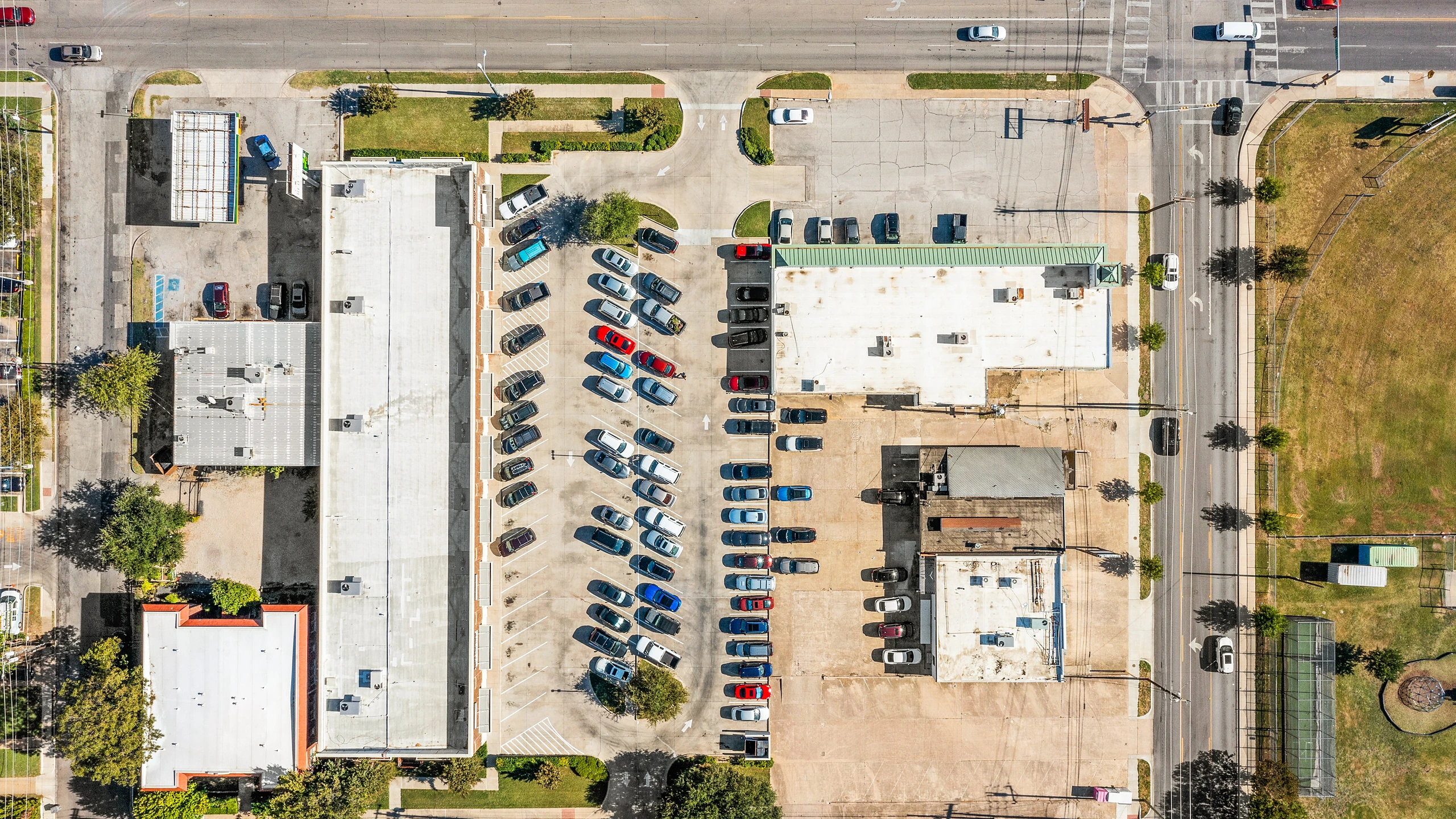 Overhead eagle-eye aerial of a strip center showing building footprint, rear service access, and parking field