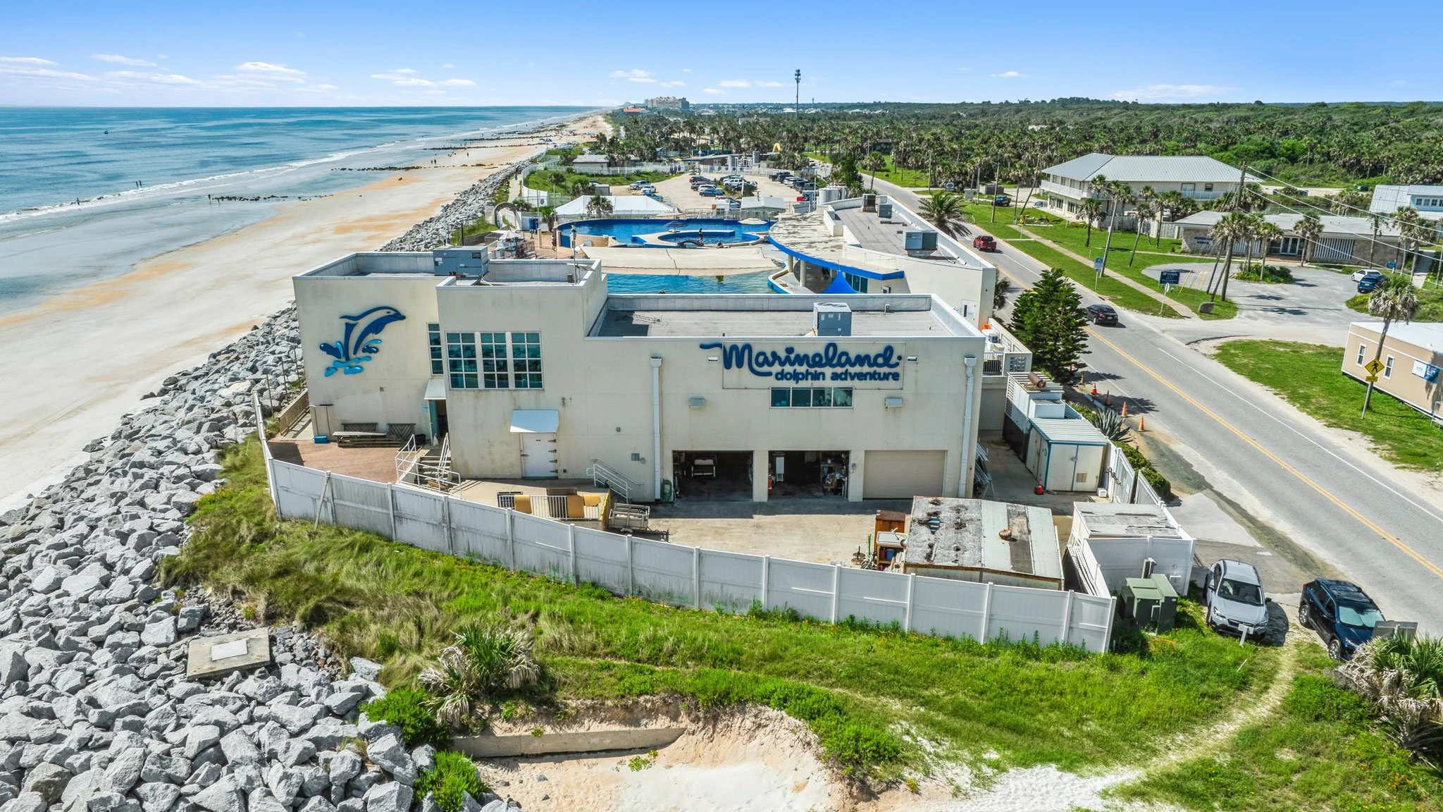 Aerial photograph of an oceanfront single-tenant entertainment and attraction property with pools, parking, and highway frontage